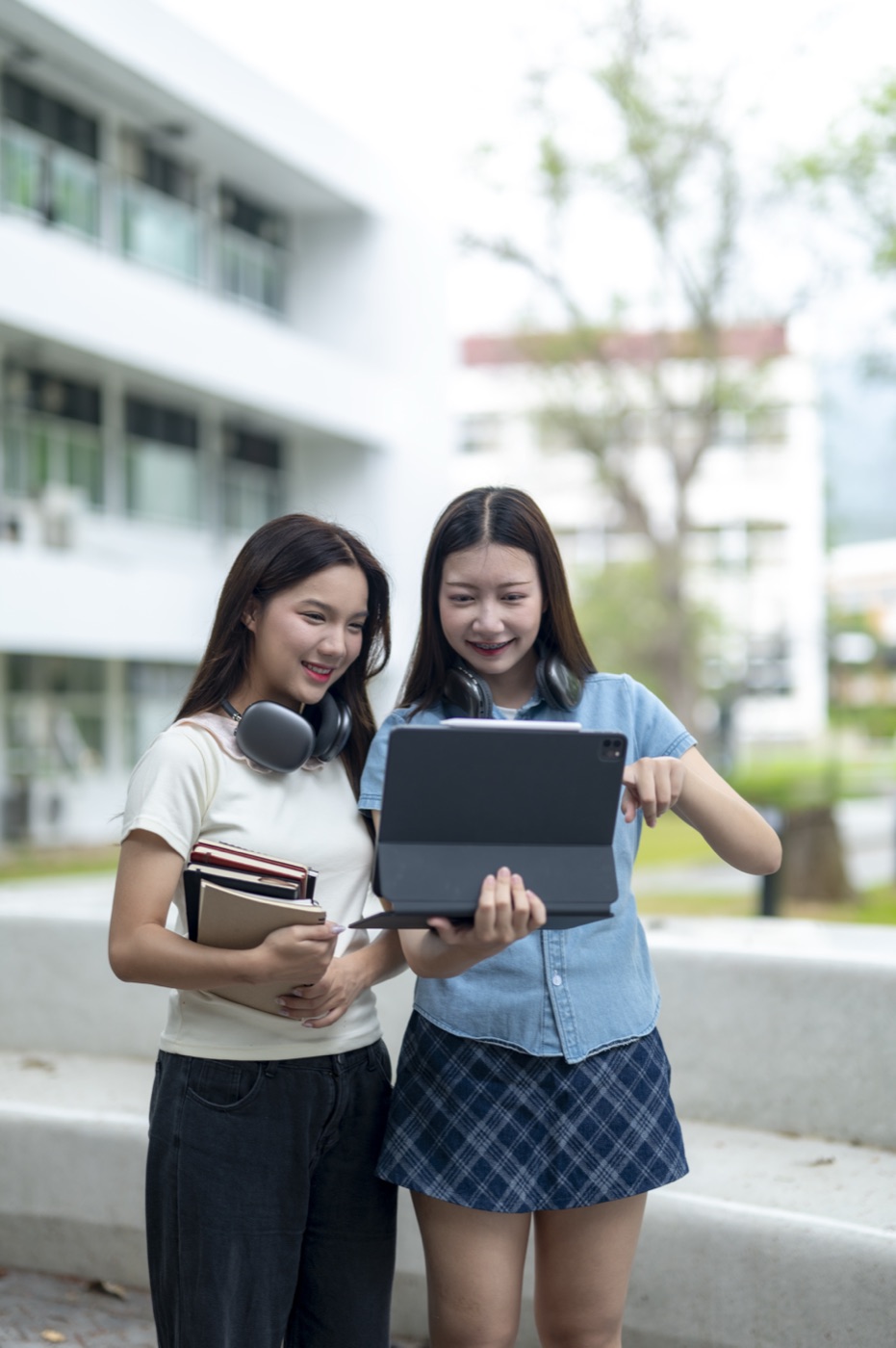 Happy students studying together outdoors on a table with a tablet